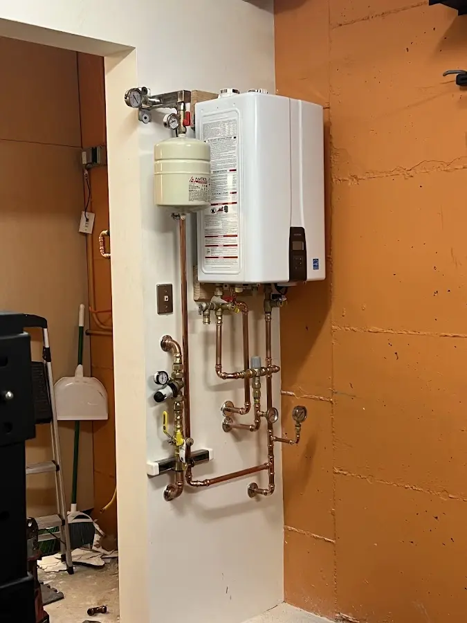 Plumbing technician inspecting water heater connections in Northfield